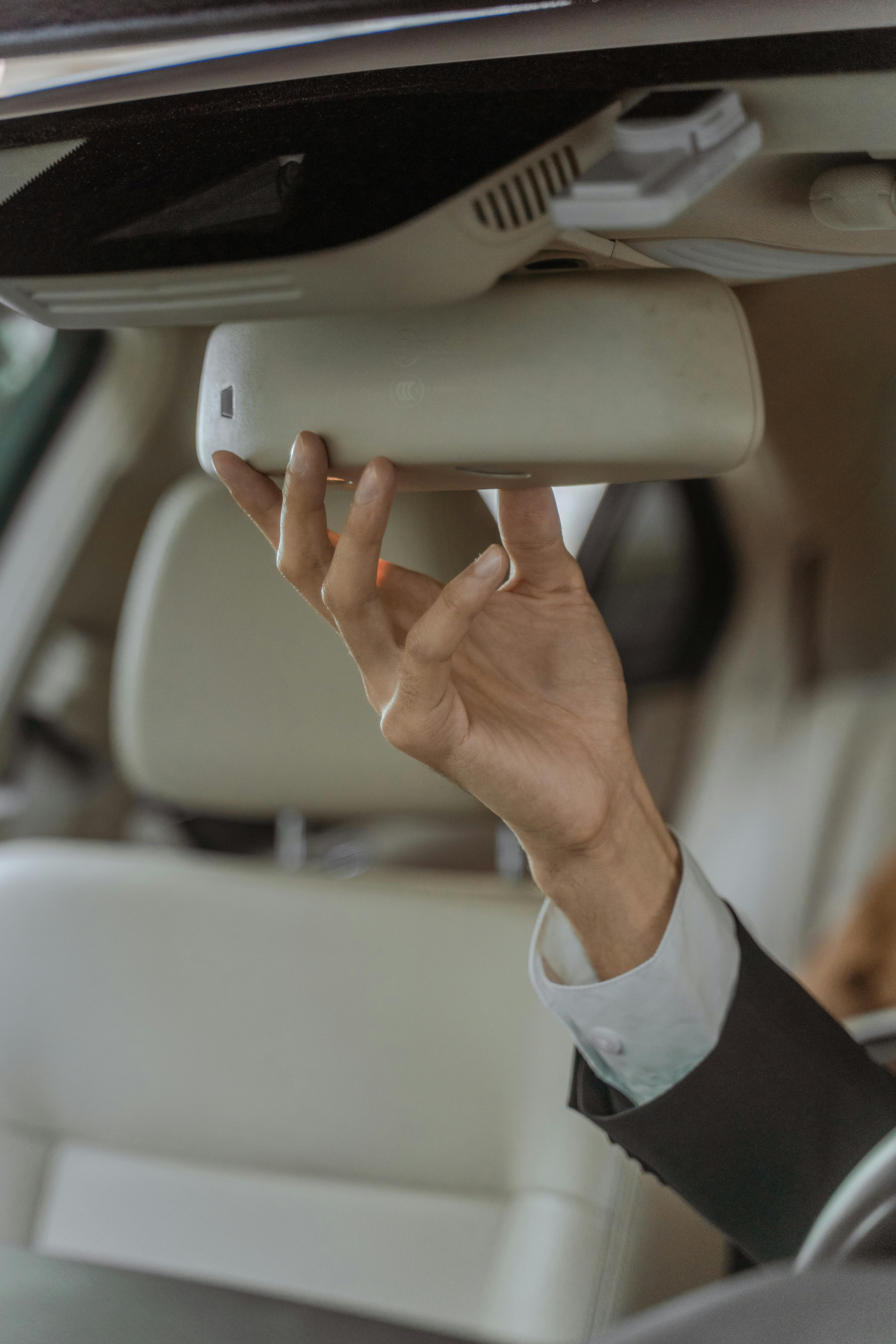 Professional Chauffeur adjusting the mirror of interior of a car